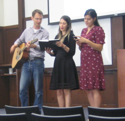Leading song service with guitar and two girls.